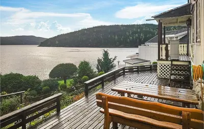 a wooden deck with a bench and a view of a lake at 3 Bedroom Lovely Home In Mosvik in Mosvik