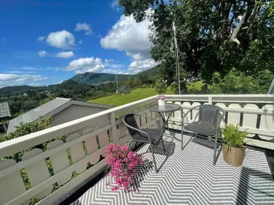 a balcony with two chairs and a table with flowers at Nakkentunet - familievennlig hus på gårdstun. in Ørskog