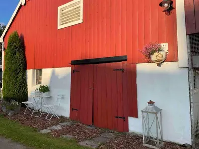 a red and white barn with a red door at Nakkentunet - familievennlig hus på gårdstun. in Ørskog
