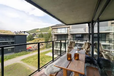 a view from the balcony of a house with a wooden table at Spacious and modern apartment in the heart of Geilo, perfect year round! in Geilo