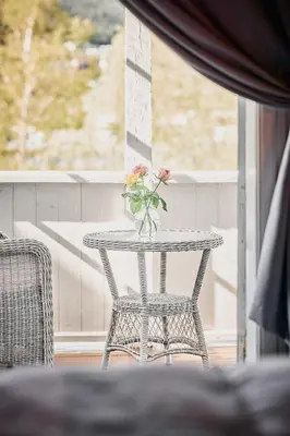 a table with a vase of flowers on a balcony at Visnes Hotel Stryn in Stryn
