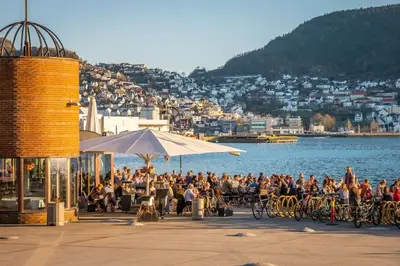 a group of people sitting on a pier near the water at Dinbnb Apartments I Historical Two-Floor Apartment with Rooftop Panorama I 1645 Heritage in Bergen