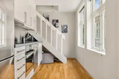 a kitchen with white cabinets and a staircase at Dinbnb Apartments I Historical Two-Floor Apartment with Rooftop Panorama I 1645 Heritage in Bergen