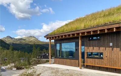 a building with a grass roof with mountains in the background at 4 Bedroom Nice Home In Tuddal in Tuddal