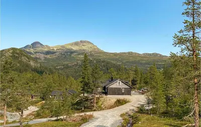 a house on a road with mountains in the background at 4 Bedroom Nice Home In Tuddal in Tuddal