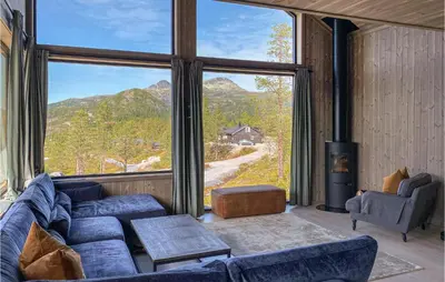 a living room with a blue couch and a large window at 4 Bedroom Nice Home In Tuddal in Tuddal