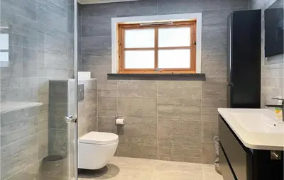 a bathroom with a toilet and a sink and a window at 4 Bedroom Nice Home In Midsund in Midsund