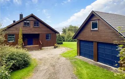a barn with a blue garage door next to a house at 4 Bedroom Nice Home In Midsund in Midsund