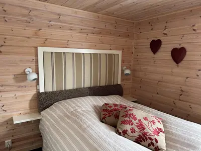 a bedroom with a bed with wooden walls and hearts on the wall at Saballie - Cosy cabin - sunny location! in Slåtto