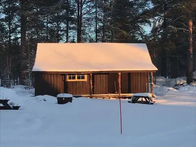 a cabin with a snow covered roof in the snow at Båtstø Camping in Elga