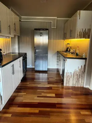 a kitchen with wooden floors and a stainless steel refrigerator at Leilighet for korttidsleie in Otta