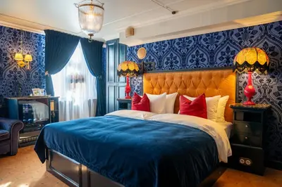 a bedroom with a bed with blue walls and red pillows at Charmante Skostredet Hôtel in Bergen
