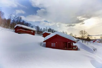 a red cabin in the snow with snow on the ground at Kvetos naturopplevelser in Beitostøl