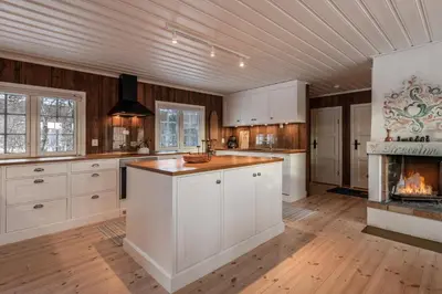 a kitchen with white cabinets and a fireplace at Sunny and beautiful cabin in Geilo in Geilo