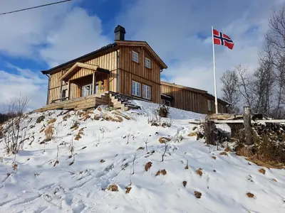 a house on top of a snow covered hill with a flag at Sunny and beautiful cabin in Geilo in Geilo