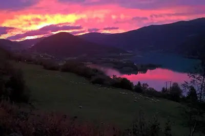 a sunset over a field with a lake and mountains at Feriebolig i Garmo in Lom