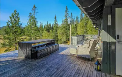 a deck with a fireplace and chairs on a house at Awesome Home In Hjartdal With Kitchen in Hjartdal