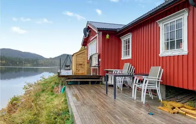 a red house with a table and chairs on a dock at Nice Home In Follafoss With Lake View in Sela