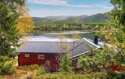 a red cabin on the shore of a lake at Nice Home In Follafoss With Lake View in Sela