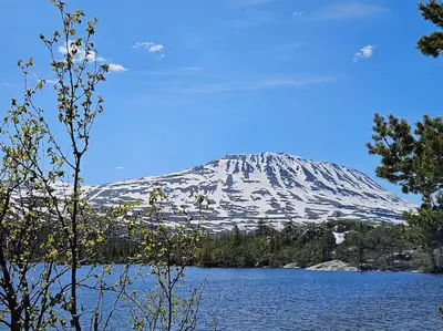 a snow covered mountain with a lake in front of it at Fin leilighet med flott utsikt til Gaustatoppen in Rjukan