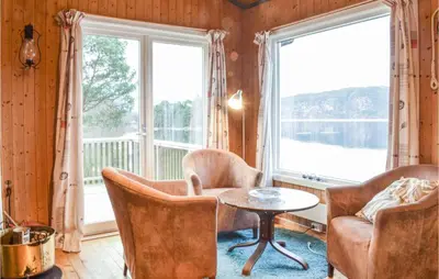 a living room with chairs and a table and windows at Nice Home In Eikelandsosen With Sauna in Eikelandsosen