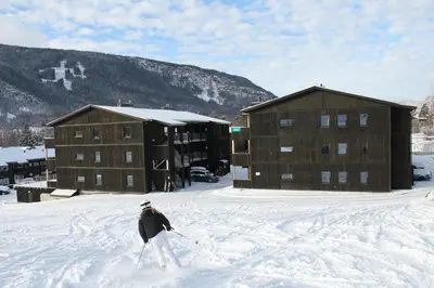 a person on skis in the snow in front of buildings at Hafjelltunet in Hafjell