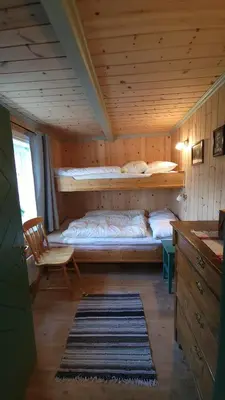 a bedroom with a bed and a chair in a room at Hallingstue by Hallstensgaard - Geilo in Geilo