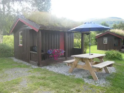a picnic table and an umbrella next to a cabin at Smegarden Camping in Oppdal