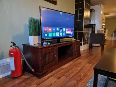 a flat screen tv on a wooden stand with a fire extinguisher at Kjellerleilighet egen inngang. in Stange