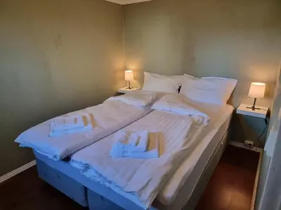 a large bed with white sheets and towels on it at Kjellerleilighet egen inngang. in Stange