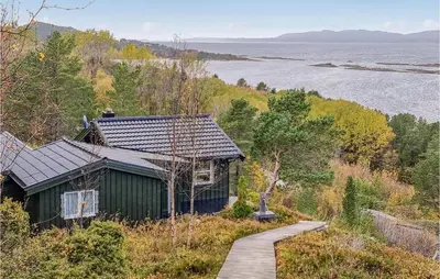 a building on a hill with a walkway next to a lake at Cozy Home In Kjørsvikbugen With Wifi in Taftøya