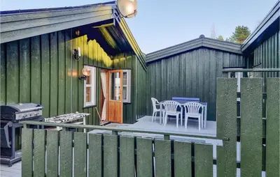 a green house with a table and chairs on a patio at Cozy Home In Kjørsvikbugen With Wifi in Taftøya