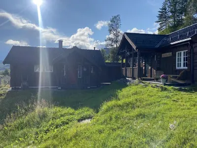 a house with a grass yard in front of it at Cottage Yard - cozy Cabin in Geilo