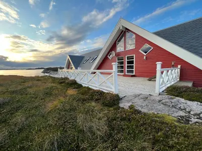 a red house with a white fence on a beach at Atlantic Road Seaside Housing in Averoy