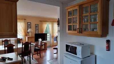 a kitchen and a living room with a microwave at Feriehus Voldstad in Syvde