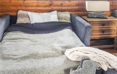 a bed with a blanket on it next to a night stand at Beautiful Home In Bjorli in Bjorli