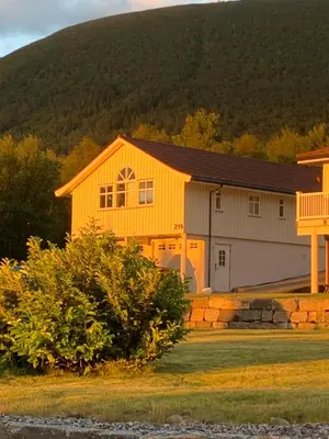 a yellow house with a mountain in the background at Sivert´s kontorhotell in Tomrefjord