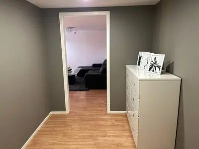 a room with a white dresser and a living room at A Cozy Place To Stay Over in Tysvær