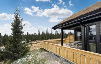 a house with a wooden deck next to a tree at Cozy Home In Sjusjøen With Kitchen in Sjusjøen