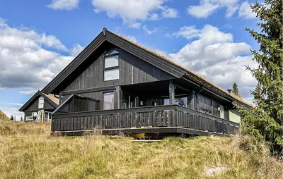 a black house sitting on top of a hill at Cozy Home In Sjusjøen With Kitchen in Sjusjøen