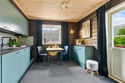 a kitchen with blue cabinets and a table with chairs at Hygge Hütte - zwischen Fjell und Fjord in Lauvstad