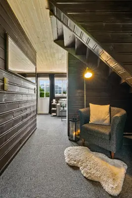 a living room with a couch and a chair and stairs at Hygge Hütte - zwischen Fjell und Fjord in Lauvstad