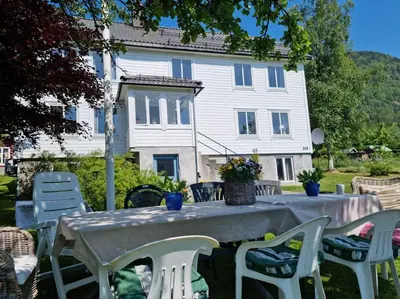 a table and chairs in front of a white house at Kavli gjestehus - Isfjorden. in Isfjorden