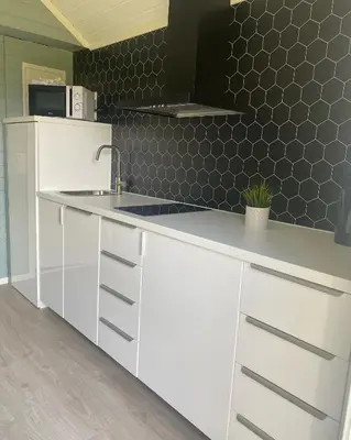 a kitchen with white cabinets and a white counter top at Nygård Camping in Hjelle