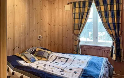 a bedroom with a bed with wooden walls and a window at Cozy Home In Østby With Wifi in Trysil