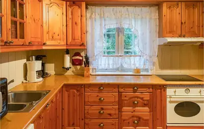 a kitchen with wooden cabinets and a window at Cozy Home In Østby With Wifi in Trysil