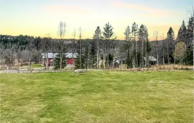 a large grass field with a red barn in the background at Cozy Home In Østby With Wifi in Trysil
