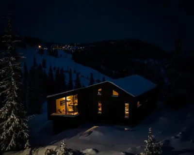 a black house in the snow at night at Ski-in-out hytte på Kvitfjell in Strande