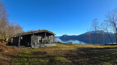 a small shack on a hill next to a lake at Bregnehytte in Leikanger