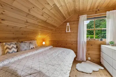 a bedroom with a bed in a wooden room at Fjord Lodge direkt am Ufer des Dalsfjord in Lauvstad